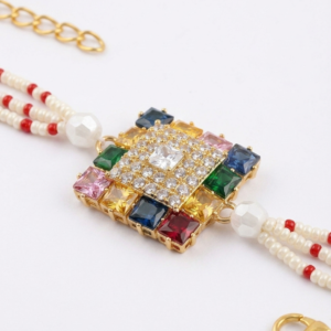 RichMade premium Navratna crystal bracelet rakhi with multicolor stones, cubic zirconia centerpiece, pearl bead strands, and gold clasp for Raksha Bandhan