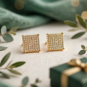 Gold square crystal stud earrings on a cream surface